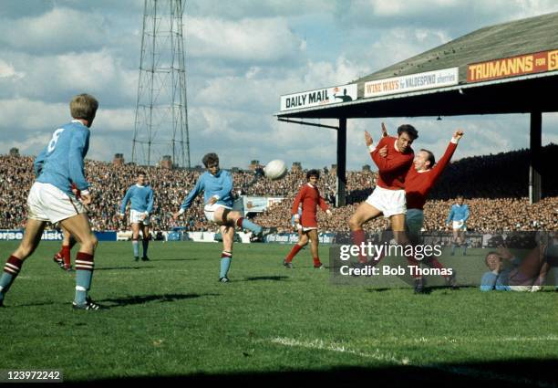 Manchester City striker Bobby Owen shoots as Manchester United defenders David Sadler and Nobby Stiles attempt to block his shot, watched by George...