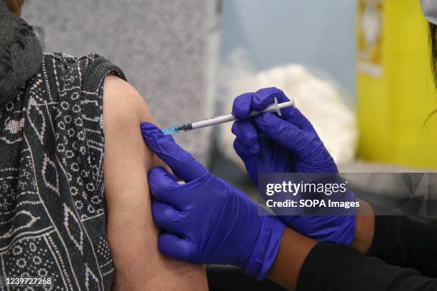 Vaccinator, administers the Pfizer COVID-19 second booster jab to a woman, at a vaccination centre in London. Older adults have been invited for a...