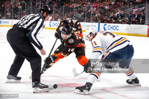 Adam Henrique of the Anaheim Ducks and Ryan McLeod of the Edmonton Oilers battle for a face-off as linesman Ryan Daisy looks on after dropping the...