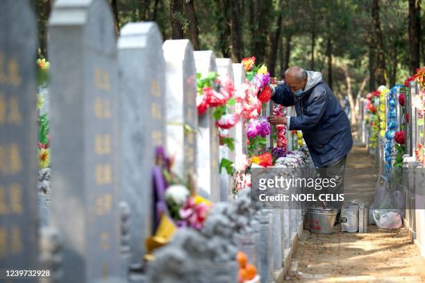 An elderly man sweeps a tomb at the Babaoshan People's Cemetery in Beijing, a day before the annual Tomb-Sweeping festival, also known as Qingming...