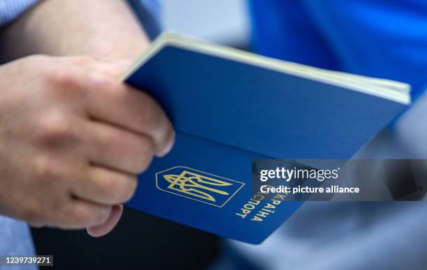 May 2022, Mecklenburg-Western Pomerania, Schwerin: A Ukrainian passport is scanned by staff at the central registration office for Ukrainian refugees...