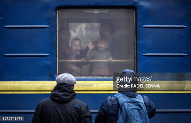 Children wave from a train at Kramatorsk central station as families flee the eastern city of Kramatorsk, in the Donbass region on April 4 amid...