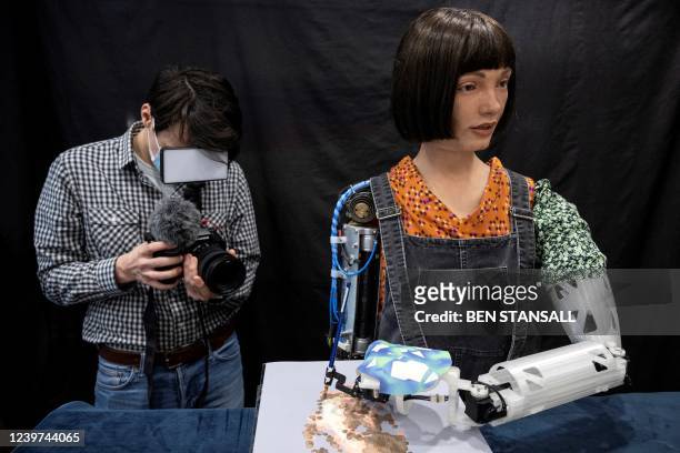 'Ai-Da', an ultra-realistic robot paints an image during a photocall in central London, on April 4, 2022. - Ai-Da is the world's first...