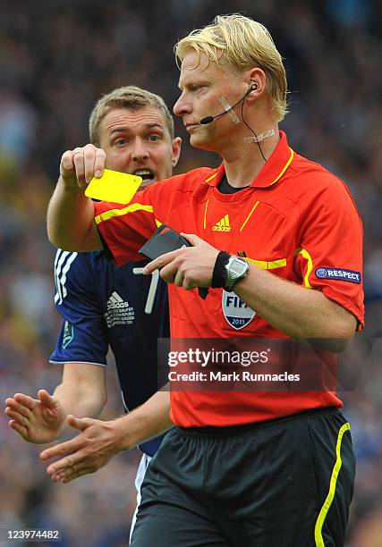 Christophe Berra of Scotland receives a yellow card from Referee Kevin Blom during the UEFA EURO 2012 Group I Qualifying match between Scotland and...