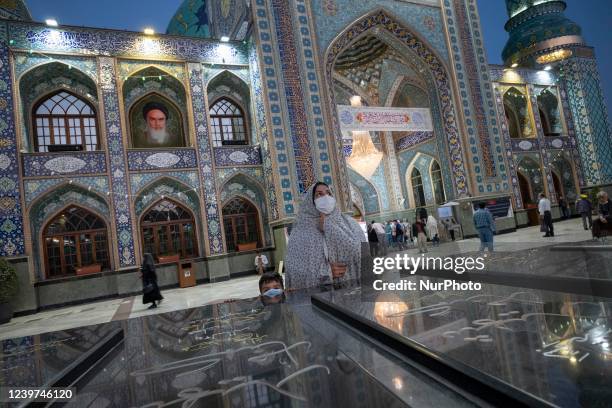 An Iranian veiled woman in white chador prays as she stands with her young son next to the graves of Iran-Iraq war unknown martyrs in a holy shrine...