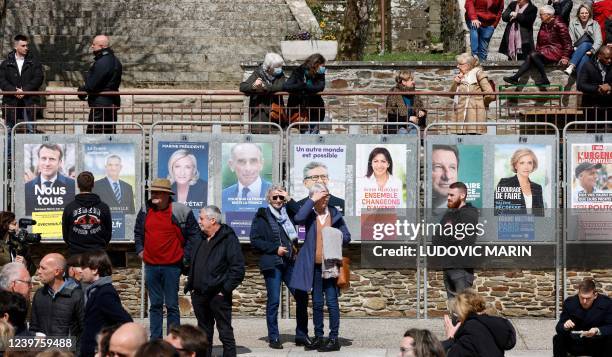 Local residents stand on the main square, next to the official posters of presidential candidates, during the visit of French President and liberal...