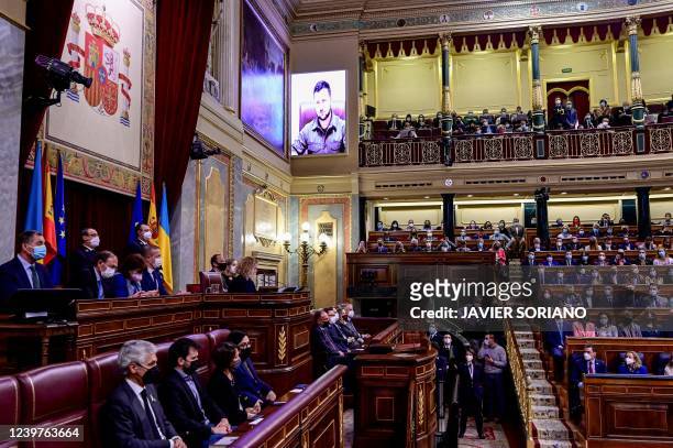 Ukrainian President Volodymyr Zelensky appears on a screen to address the lower house by videoconference, at the Spanish Parliament in Madrid on...