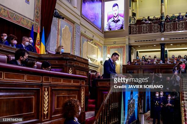 Spain's Prime Minister Pedro Sanchez delivers a speech as Ukrainian President Volodymyr Zelensky appears on a screen to address the lower house by...