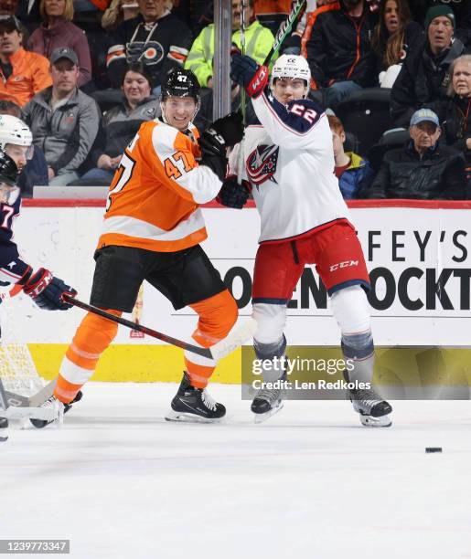 Ronnie Attard of the Philadelphia Flyers lifts the stick of Jake Bean of the Columbus Blue Jackets as they battle for the loose puck at the side of...