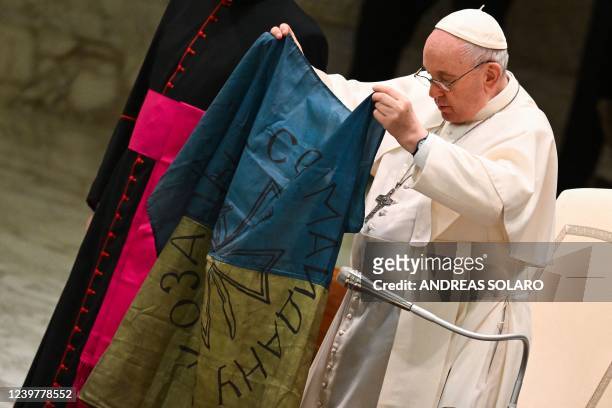 Pope Francis holds a flag of Ukraine that comes from the city of Bucha, one of the areas around Ukraine's capital from which Russian troops have...