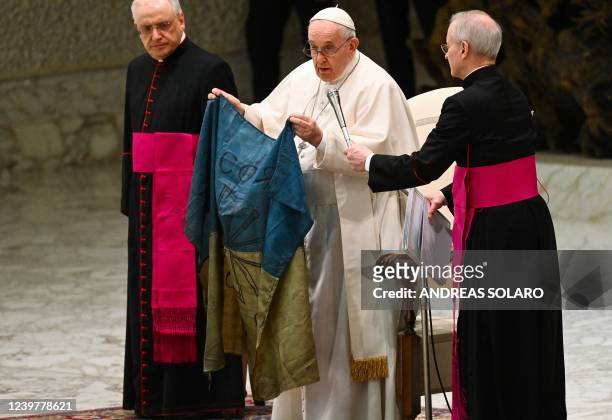 Pope Francis holds a flag of Ukraine that comes from the city of Bucha, one of the areas around Ukraine's capital from which Russian troops have...