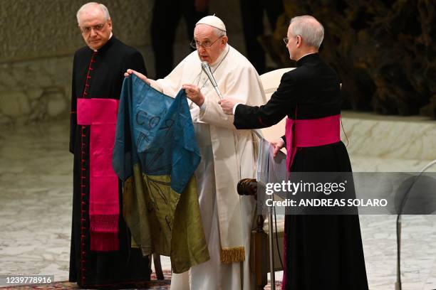 Pope Francis speaks while holding a flag of Ukraine that comes from the city of Bucha, one of the areas around Ukraine's capital from which Russian...