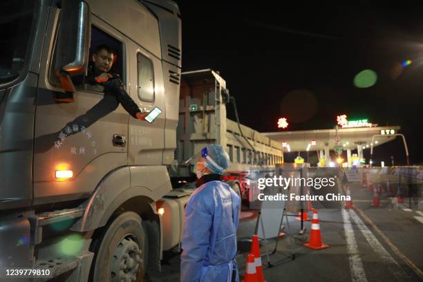 Truck driver shows his Covid-19 risk code to a government worker at an expressway checkpoint in Hangzhou in east China's Zhejiang province Tuesday,...