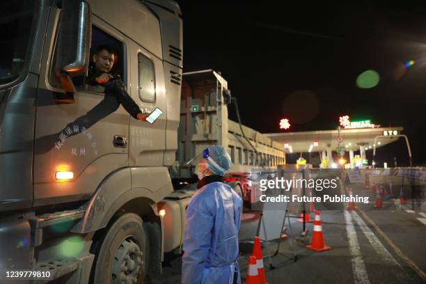 Truck driver shows his Covid-19 risk code to a government worker at an expressway checkpoint in Hangzhou in east China's Zhejiang province Tuesday,...
