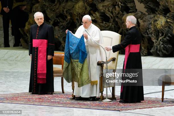 Pope Francis shows a flag that he said was brought to him from Bucha, Ukraine, during his weekly general audience in the Paul VI Hall, at the...