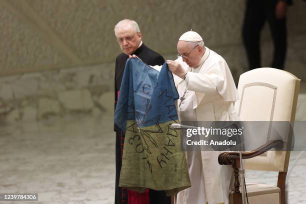 Pope Francis holds an Ukrainian flag brought to him from Bucha, during his weekly general audience in the Paul VI hall at the Vatican City Vatican,...