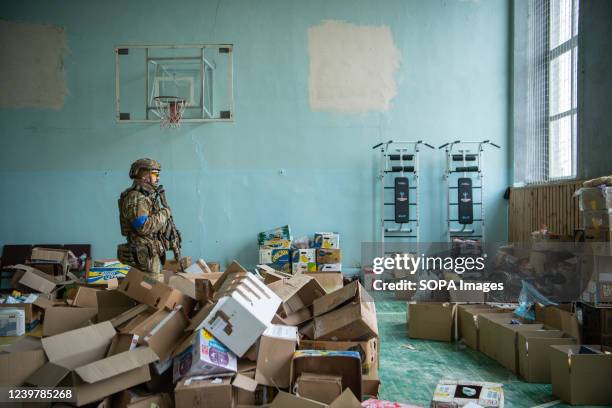 Soldier stands in a community centre filled with discarded boxes used to carry humanitarian aid in a community centre in Borodyanka, a town recently...