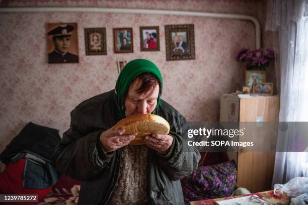 An elderly woman smells bread brought to her by volunteers inside her house in Irpin, which was damaged by shelling. Russia invaded Ukraine on 24...