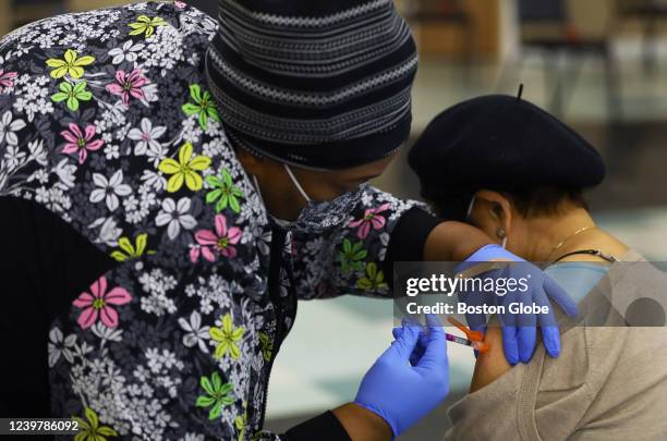 An RN administers a second booster to a patient at a COVID-19 testing and vaccination site at the Harvard Street Neighborhood Health Center in...