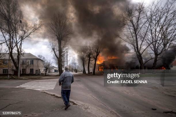 Man walks on a pavement as a house is burning following a shelling Severodonetsk, Donbass region, on April 6 as Ukraine tells residents in the...