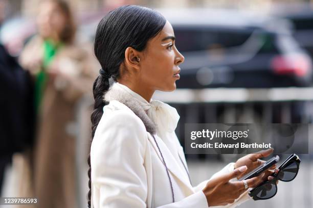 Guest wears a white coat, small earrings, outside Bevza, during New York Fashion Week Fall Winter 2020, on February 09, 2020 in New York City.