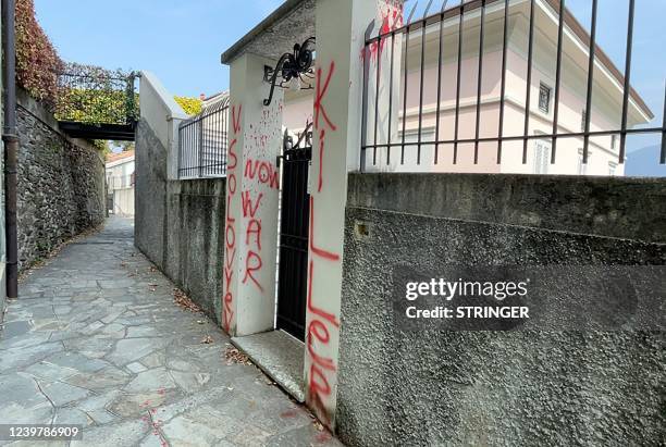 This photo obtained from Italian news agence Ansa shows anti-war slogans and red paint sprayed on the entrance to a villa in Pianello del Lario,...