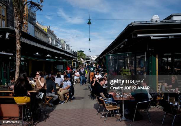 People eat and drink on sunny day at a crowded Naschmarkt market in Vienna, Austria on April 6, 2022.