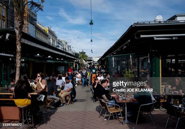 People eat and drink on sunny day at a crowded Naschmarkt market in Vienna, Austria on April 6, 2022.