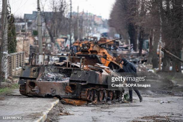 Man looks at a destroyed Russian tank in Irpin, a town near Kyiv from which occupying Russian troops recently withdrew following intense fighting...