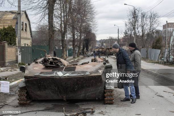 Civilians inspect the wreckage of a tank in the town of Bucha, on the outskirts of Kyiv, after the Ukrainian army secured the area following the...