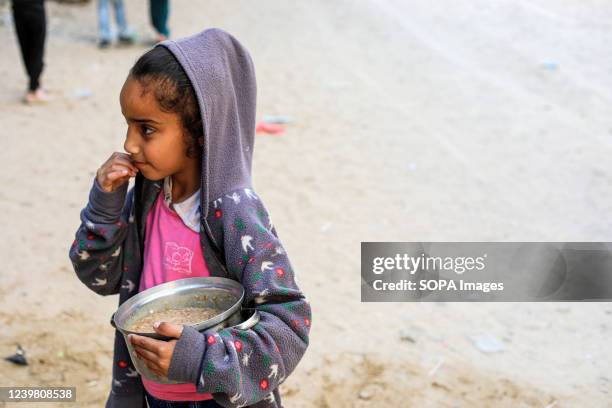 Palestinian little girl seen happy after receiving soup from a center of a local charity group that offers free food during the holy month of Ramadan...