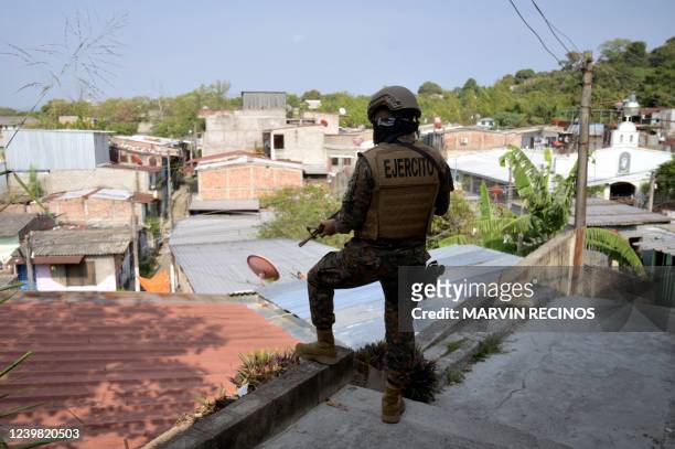 Salvadorean soldier stands guard as inmates of the "La Esperanza" prison paint over graffiti linked to the Mara Salvatrucha gang, at the 22 de Abril...