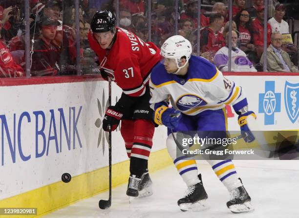 Andrei Svechnikov of the Carolina Hurricanes and Casey Fitzgerald of the Buffalo Sabres battle for a puck along the boards during an NHL game on...