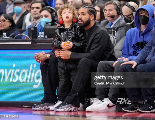 Drake sits with his son Adonis while the Toronto Raptors play the Philadelphia 76ers during the first half of their basketball game at the Scotiabank...