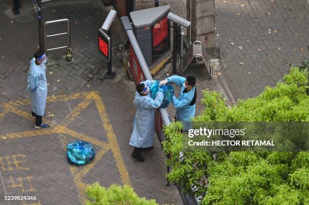 Guard, wearing personal protective gear, receives goods from a delivery worker in a compound during a COVID-19 lockdown in the Jing'an district in...