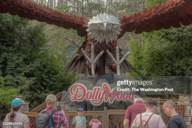 Visitors pose for photographs in front of a sign at Dollywood in Pigeon Forge, Tennessee on Wednesday, March 30, 2022. Dollywood reopened for its...