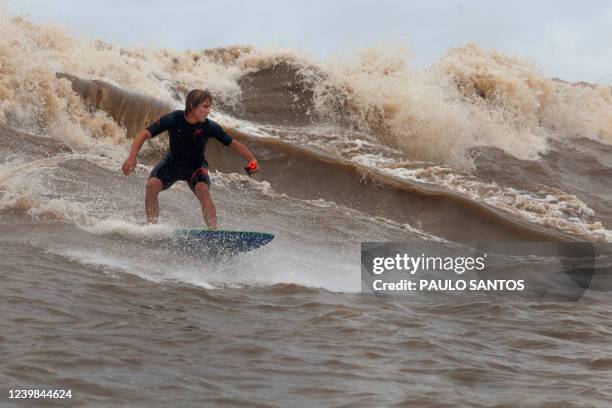 Brazilian surfer Lucas Fink drops a wave into the waters of the mouth of the Amazon River, in an area known as Canal do Perigoso, to catch the waves...