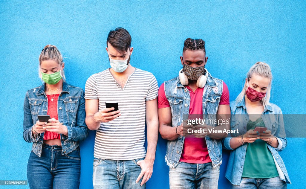 Multiraciale vrienden met gezichtsmaskers die het volgen app met mobiele smartphones gebruiken - Jonge milleniale mensen die inhoud op sociale medianetwerken delen - Nieuw normaal levensstijlconcept - Helder levendig filter