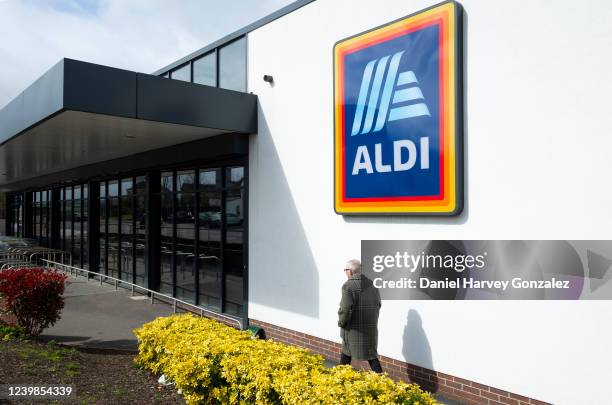 An elderly man passes the brand's logo on his way into the shop, as German grocery giant Aldi announces that the prices of goods in its supermarkets...