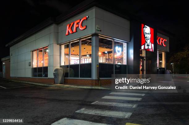 An empty branch of multinational fast food giant Kentucky Fried Chicken, or KFC, is lit up by its interior lights and the neons of its logo at night...