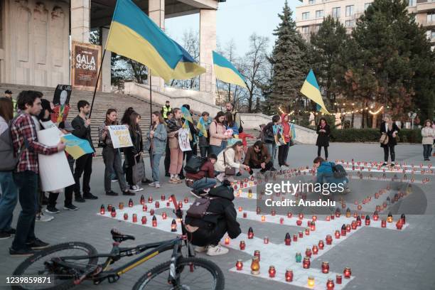 People light candles to pray for the people who lost their lives in Mariupol during protest against Russian attacks on Ukraine in front of the...