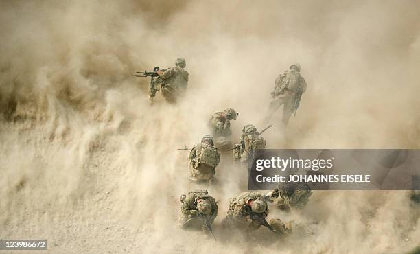 Soldiers gather near a destroyed vehicle and protect their faces from rotor wash, as their wounded comrades are airlifted by a Medevac helicopter...