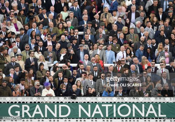 Racegoers watch during the Grand National Steeple Chase on the final day of the Grand National Festival horse race meeting at Aintree Racecourse in...