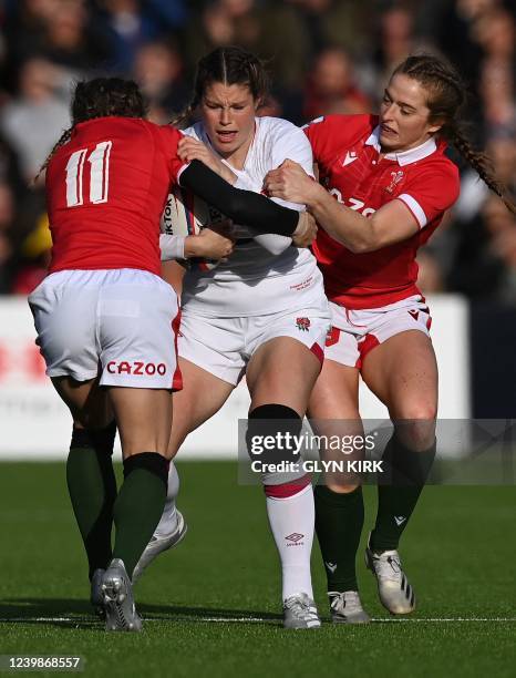 England's wing Jess Breach is tackled by Wales' wing Jasmine Joyce and Wales' wing Lisa Neuman during the Six Nations international women's rugby...