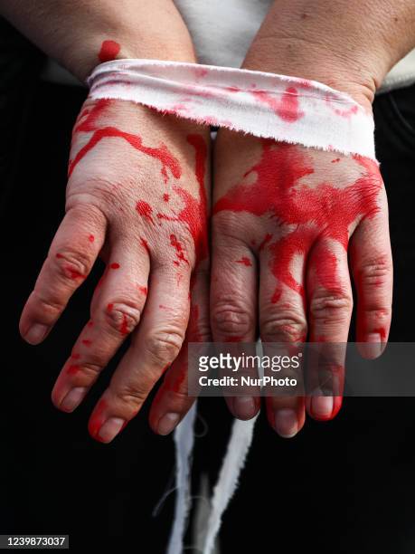 Hands of a woman painted with fake blood are seen during a silent protest at the Main Square against the mass murder of Ukrainian civilians by the...