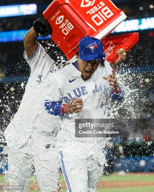 Santiago Espinal of the Toronto Blue Jays has water dumped on him by Vladimir Guerrero Jr. #27 after their MLB game victory over the Texas Rangers at...