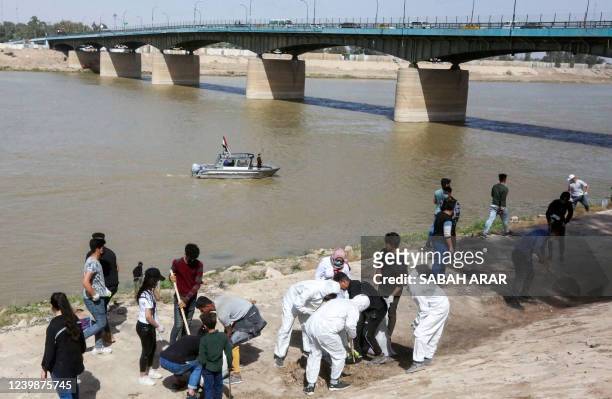 Young Iraqi volunteers take part in a clean-up campaign on the bank of the Tigris river in the Adhamiyah district of the capital Baghdad, on March...