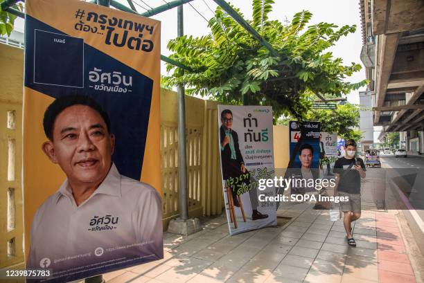 Pedestrian walks past Bangkok governor election campaign posters showing candidates Aswin Kwanmuang, Sakontee Pattiyakul and Suchatvee Suwansawat...