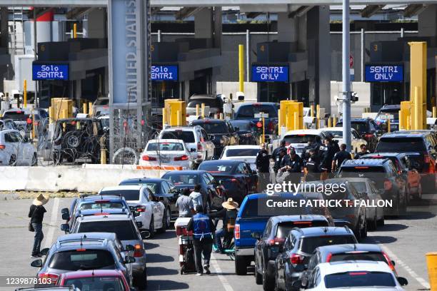 Authorities handcuff a person as vehicles wait to enter the United States Customs and Border Protection San Ysidro Port of Entry along the US-Mexico...