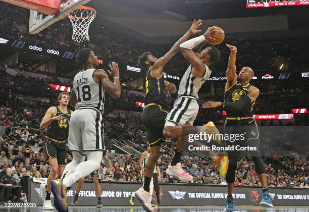 Lonnie Walker of the San Antonio Spurs tries to drive between Andrew Wiggins of the Golden State Warriors and Draymond Green in the first half at...